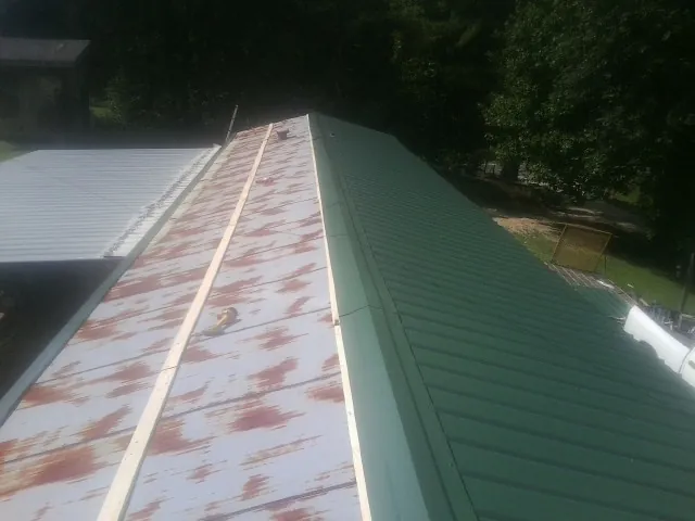 Old rusted panels beside newly installed green metal roofing — Wind Damage Roof Repair by Roofing Brothers in Van Wert