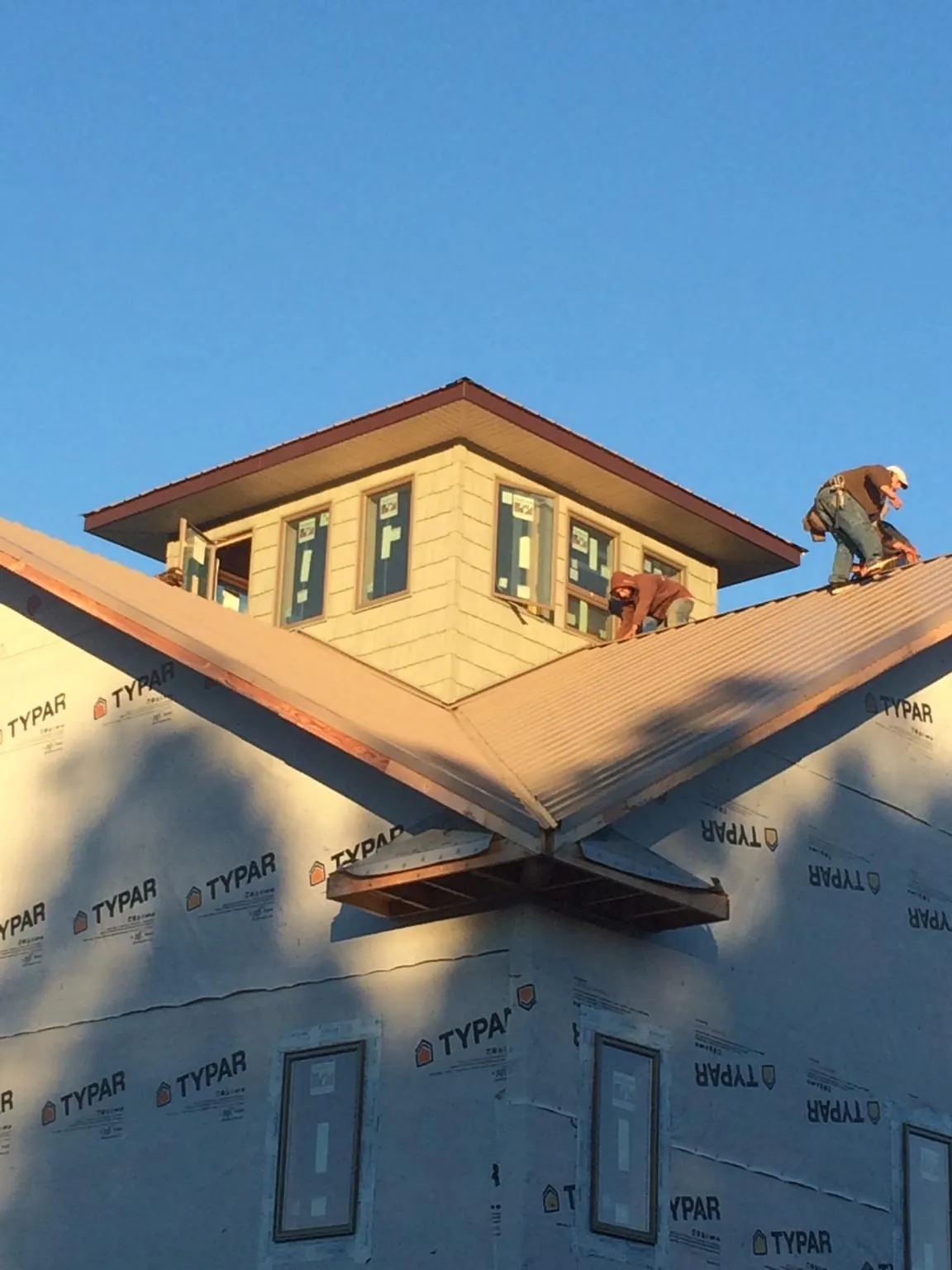 Roofers working around a rooftop cupola on a new metal roof at sunset — Roof Waterproofing in Van Wert by Roofing Brothers